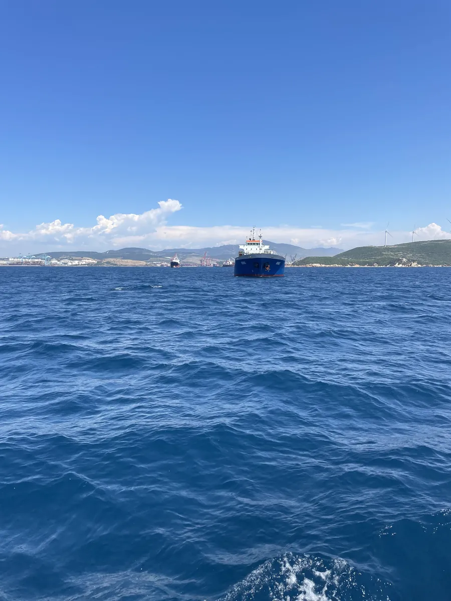 A cargo ship at anchor, seen from the launch